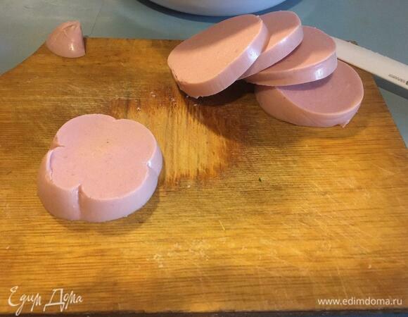 Колбасу нарезаем на пластинки, а уже их — на небольшие кубики.