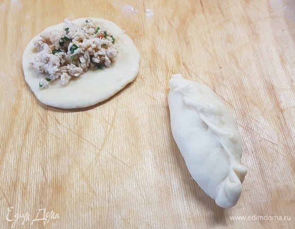 Поднявшееся тесто разделить на колобки. Каждый раскатать в лепешку и на середину выложить начинку, защипать края. Смазать пирожки яйцом и выпекать 15 минут при 170°C.