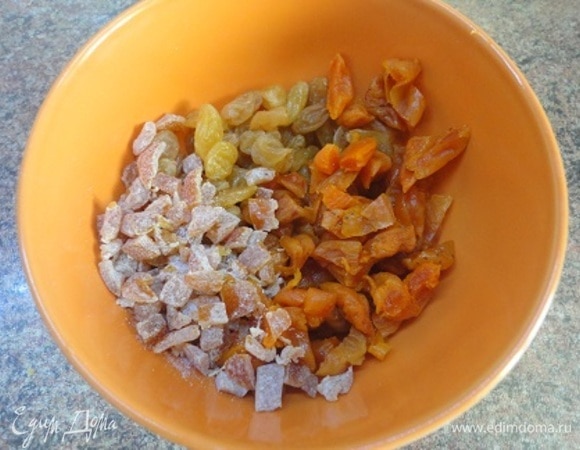 Подготовьте сухофрукты: курагу и изюм вымыть и залить горячей водой. Оставьте на 15 минут, затем откиньте на сито. Курагу нарезать кусочками.