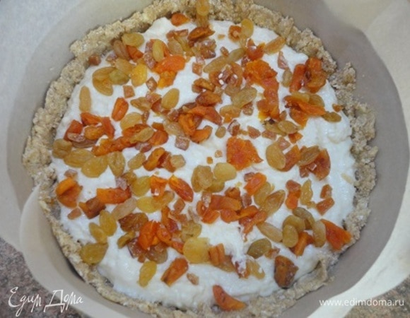 Духовку разогрейте до 200°C. Выложите в подготовленную форму творожную начинку, затем сухофрукты.