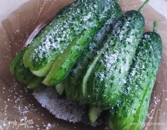 Огурцы разрезать крестом, не доходя до основания примерно 1 см. Натереть солью снаружи и внутри. Накрыть. Оставить на 30 минут.