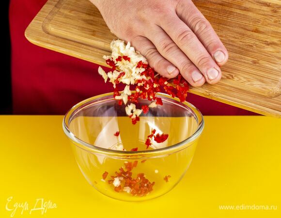 Мелко нарубите чеснок и перец чили. Выложите в чашку.