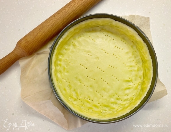 Готовое тесто раскатать на припыленной мукой поверхности и выложить в форму для запекания диаметром 23 см. Проткнуть тесто вилкой, застелить пергаментом и засыпать груз (фасоль, рис, горох), выпекать 12 минут при 180°С. Удалить бумагу и груз, выпекать еще 10 минут.