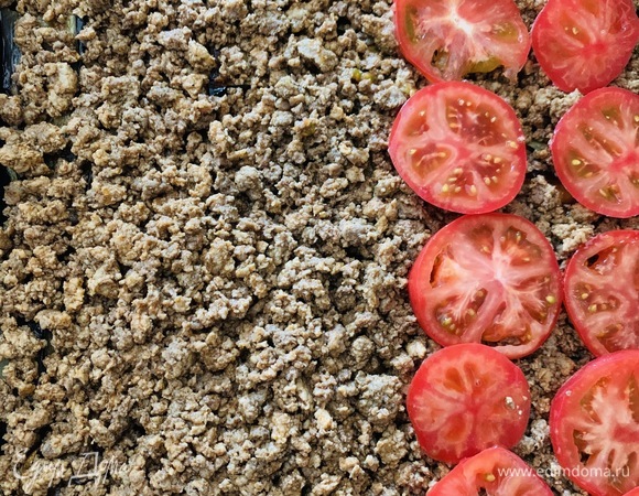 Баклажаны покрываем готовым фаршем. По желанию можно поверх фарша выложить нарезанные кружочками помидоры. В классической греческой мусаке томатов нет.