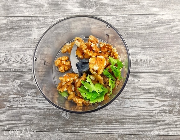 Грецкие орехи, воду, специи и зелень измельчить блендером. Либо перекрутить орехи в мясорубке и затем добавить воду, специи и рубленую зелень.