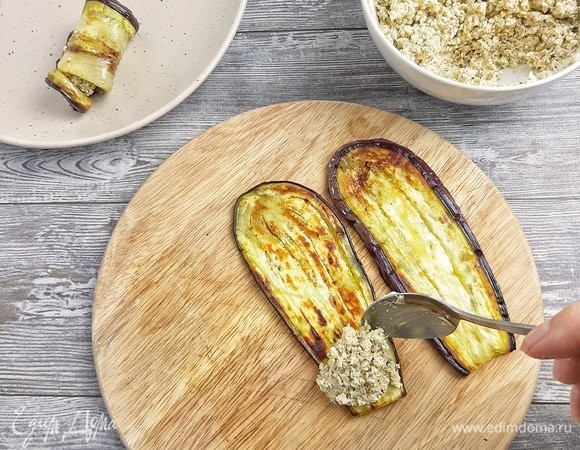 На край баклажана кладем часть ореховой начинки и скручиваем в рулетик.