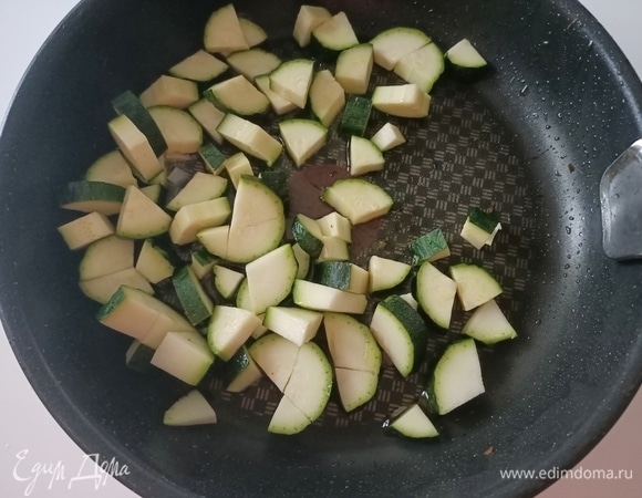 В сковороду налить оливковое масло, добавить чеснок и нарезанный цукини. Посолить, поперчить и жарить 5–7 минут до готовности.
