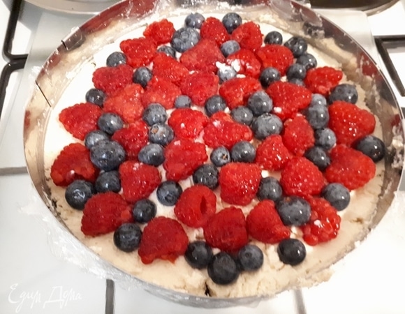 На пищевую пленку выложите слой крема, затем — 1 корж и покройте его небольшим слоем крема. Затем выложите ягоды, укройте их оставшимся кремом и уложите второй корж. Накройте тарелкой и переверните. Теперь пищевую пленку можно убрать. В принципе, в таком состоянии торт уже можно есть. Если вы хотите украсить его глазурью, то надо убрать его в морозилку на час, чтобы глазурь растекалась равномерно и не повредила верхний слой крема, поверхность торта должна быть твердой.