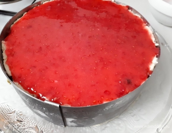 Для глазури разотрите малину с сахарной пудрой до однородного состояния. Объем сахарной пудры, может, выглядит устрашающе, но именно такая пропорция позволяет получить глазурь достаточно вязкую, чтобы она не стекала. Выньте торт из морозилки, вылейте на него глазурь и разровняйте ее.
