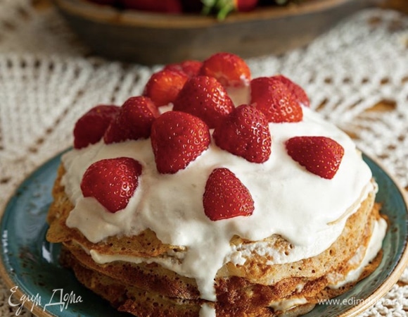 Смазываем кремом каждый блинчик, выкладывая их стопкой друг на друга. Сверху оформляем свежей клубникой или другими сезонными ягодами по вкусу.
