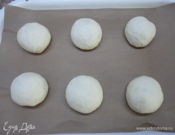 Из каждого куска теста сформировать круглую булочку, подминая края. Выложить на противень, застеленный пергаментом, сохраняя интервал между ними. Оставить на 10–20 минут.