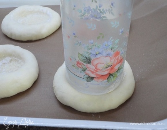 Каждую булочку придавить стаканом, предварительно обмакнув его в муку, так, чтобы образовалось углубление.