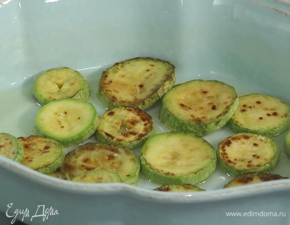 Форму для выпекания смазать оливковым маслом, на дно уложить обжаренные кабачки.