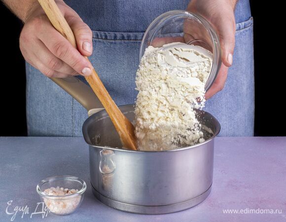 В кипящую жидкость всыпьте муку. Тщательно перемешивайте массу в течение 3 минут, пока тесто будет завариваться. Выключите плиту.