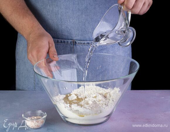 Добавьте воду и щепотку соли. Вымешивайте тесто, пока оно не станет однородным и эластичным. Скатайте тесто в шар и уберите в теплое место на 40 минут для подъема.