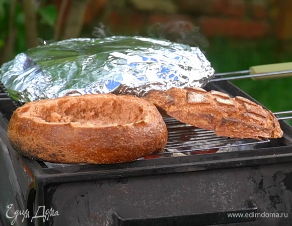 Буханку разрезать вдоль на две части, вынуть весь мякиш и прогреть обе половинки на гриле.