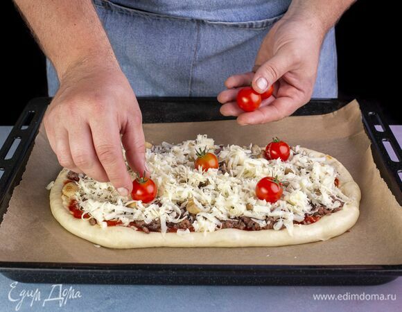 Выложите помидоры черри. Загните края пиццы по бокам и выпекайте в разогретой до 220 °С духовке 10–12 минут.