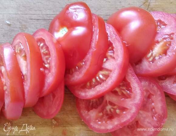 Помидоры нарезать кружочками. Выложить в форму поверх рыбы.