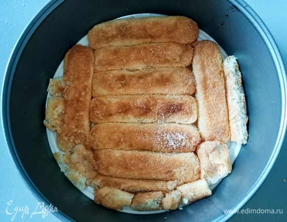 На круглое блюдо ставим кольцо от разъемной формы (24 см). Соединяем лимончелло (можно заменить на лимонный или апельсиновый сок) и воду. Окунаем в эту смесь печенье и выкладываем основу нашего будущего торта. Отправляем в холодильник.