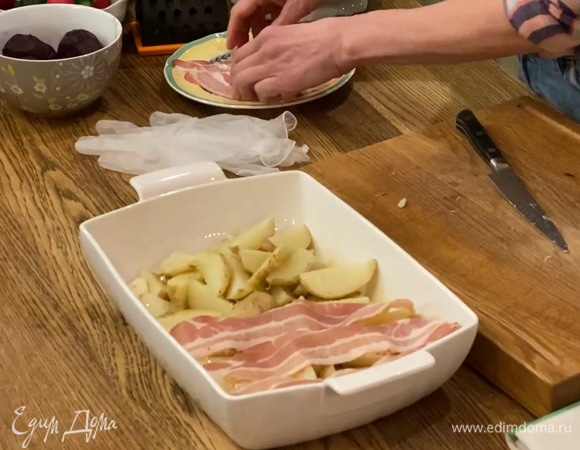 Картофель отварить в мундире почти до готовности, нарезать четвертинками, поместить в форму для запекания, сбрызнуть оливковым маслом и слегка посолить, сверху разложить чеснок и полоски бекона.