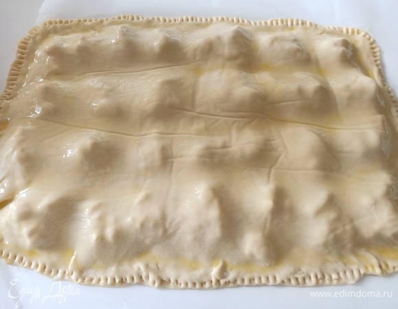 Накрываем начинку второй частью теста. Хорошо защипываем края, чтобы во время выпекания не вытекла начинка. Аккуратно перекладываем бумагу с фокаччей на противень. Смазываем верх оливковым маслом.