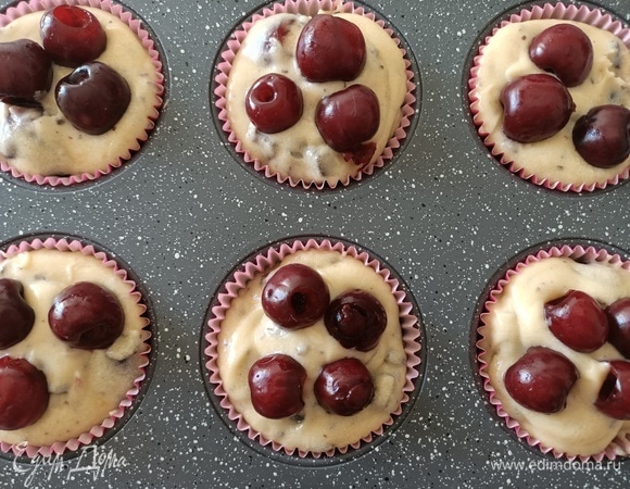 Разложить бумажные формочки в форму для выпечки, заполнить полученным тестом. Сверху выложить черешню.