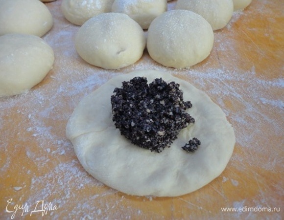 Подошедшее тесто разделить на 15 одинаковых кусков (примерно по 80 г), сформировать круглые булочки и оставить на 15 минут. За это время подготовить форму: смазать маслом и посыпать мукой. Затем каждую булочку расплющить и выложить примерно по 1 ст. ложке начинки. Защипнуть края кверху.