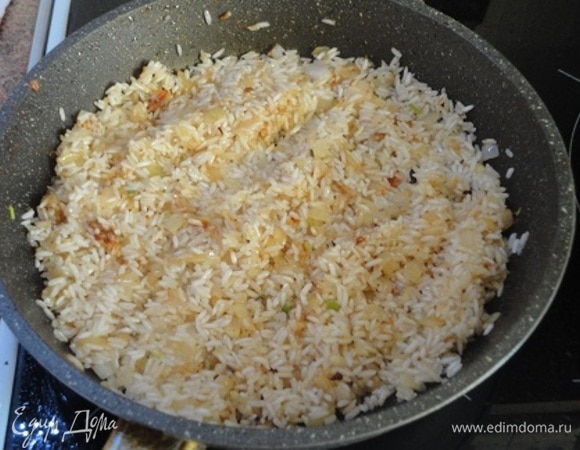 В сковороду, в которой жарилась курица, добавить лук и жарить до мягкости. Затем добавить рис, чеснок, молотый кумин и остатки специй, которые осталась в миске после натирания курицы, и обжаривать, постоянно помешивая, пока почувствуете приятный аромат специй.