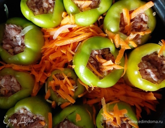 Натертую морковь и нашинкованный репчатый лук укладываем на дно кастрюли между перцами.