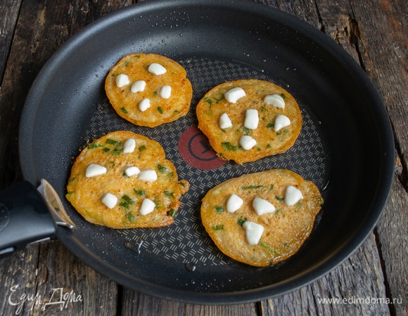 Переворачиваем оладьи, кладем сверху моцареллу, нарезанную кубиками, накрываем сковороду крышкой, готовим еще несколько минут, чтобы поджарилась другая сторона и сыр растаял.