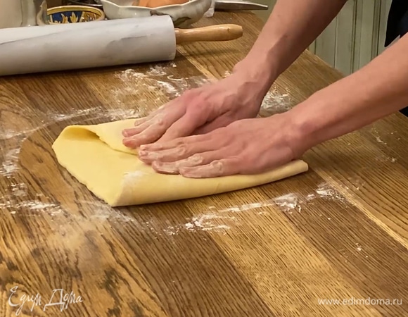 Охлажденное тесто раскатать в прямоугольник и завернуть края к центру, затем сложить пласт вдвое, так чтобы получилась «книжка». Убрать тесто в пакет и еще на 15 минут поместить в морозилку.