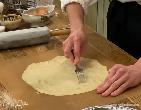 Тесто чуть придавить скалкой и разделить на 8 частей, 7 из них убрать в пакет и в морозилку, оставшуюся часть раскатать сначала на рабочей поверхности, затем на бумаге для выпечки в тонкий корж, накрыть тарелкой и обрезать лишние края. Часто наколоть тесто вилкой, переложить вместе с бумагой на противень и выпекать в разогретой духовке 5–7 минут. Так же выпечь остальные коржи и полностью остудить.