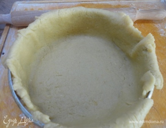 Раскатать две трети теста в круг толщиной 6 мм. Аккуратно перенести с помощью скалки в форму. Срезать лишнее тесто.