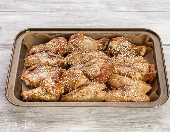 Выложите крылья в форму, посыпьте сверху кунжутом и запекайте в духовке при 180 °С около 45 минут.