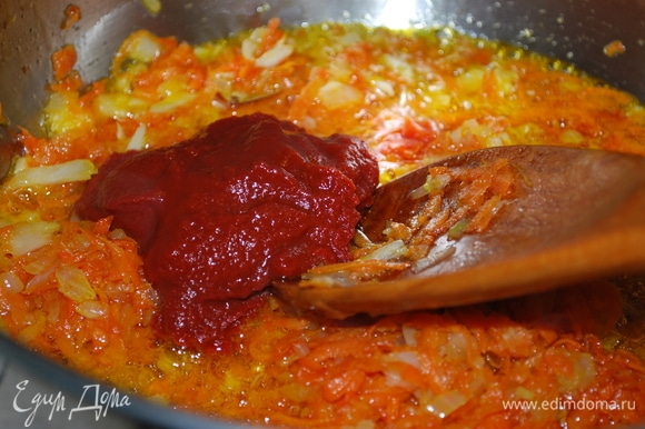 Когда морковь и лук хорошо зажарятся, добавить томатную пасту, щепотку сахара и обжаривать все вместе 2–3 минуты.