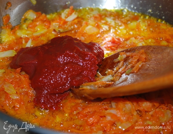 Когда морковь и лук хорошо зажарятся, добавить томатную пасту, щепотку сахара и обжаривать все вместе 2–3 минуты.