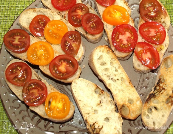 Кладем подсушенный хлеб на блюдо. Выкладываем на хлеб томаты.