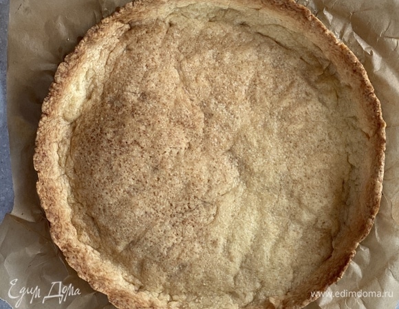 Приготовим песочное тесто. Масло и сахарную пудру взбить в чаше миксера до получения кремообразной массы. Добавить яичный желток, перемешать, добавить просеянную муку, перемешать. Сформировать из получившегося теста шар, завернуть в пищевую пленку. Охлаждать не менее 2 часов. Готовое тесто раскатать на припыленной мукой поверхности и выложить в форму диаметром 24 см. Проткнуть тесто вилкой, застелить пергаментом и засыпать груз (фасоль, рис, горох). Выпекать 15 минут при 180°C. Удалить бумагу и груз. Выпекать еще 10 минут.