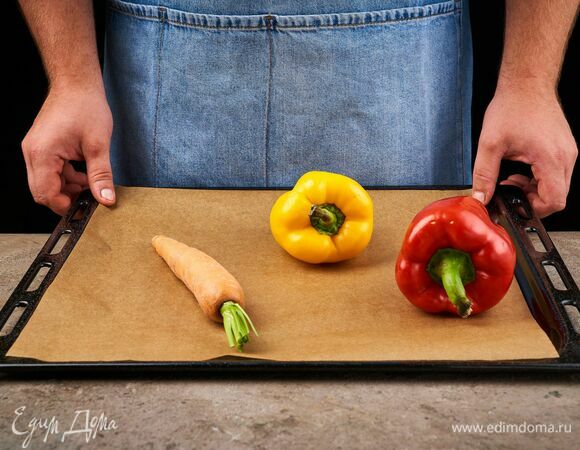 Перцы и морковь целиком выложите на противень, застеленный пергаментной бумагой, и запекайте 20 минут при 210 °C.