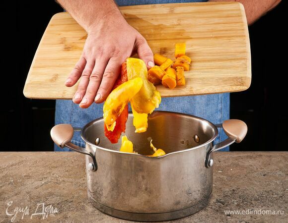 Снимите с перцев кожицу, удалите семена и перегородки. Порубите их и добавьте в кастрюлю. Несколько ломтиков оставьте для подачи.