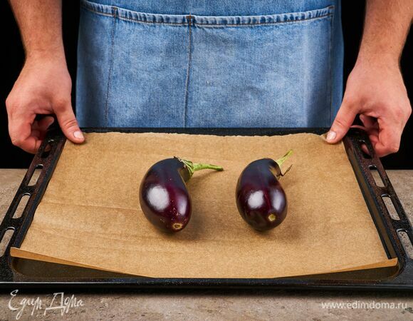 Баклажаны выложите на противень, застеленный пергаментной бумагой, и запекайте в духовке при 200 °C 30 минут.