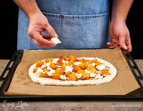 Тесто выложите на противень, застеленный пекарской бумагой, сформировав овал. Сверху выложите тыкву и сыр. Выпекайте при 190 °C около 15 минут.