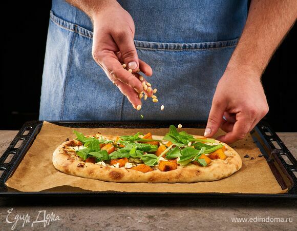 Выложите на пинцу шпинат, посыпьте кедровыми орешками.