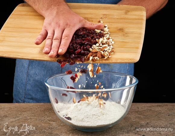 Миндаль слегка раздробите скалкой и высыпьте в муку. Добавьте вяленую клюкву и перемешайте.