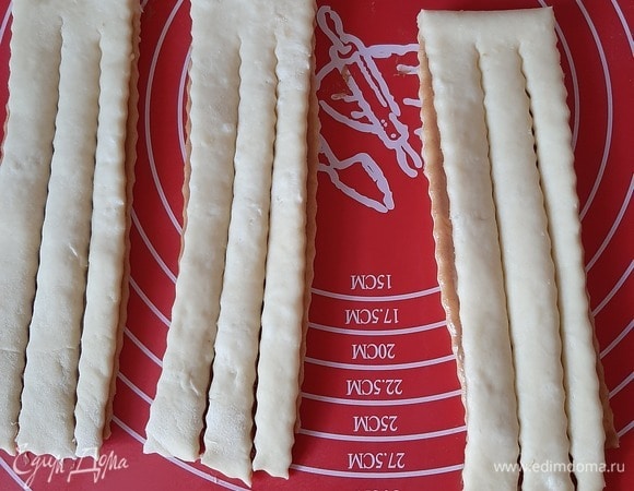 Разрезаем получившийся пласт теста на 8 частей с шагом в 5 см. Отступая от самого основания около сантиметра, разрезаем получившиеся полоски еще на три части.