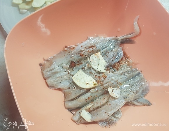 Чеснок нарезать пластинками. С мойвы слить маринад. На дно миски налить немного оливкого масла, выложить слой мойвы, выложить пластинки чеснока, посыпать паприкой, полить маслом. Можно посыпать острым перцем. Так продолжать, пока не закончится рыба. Поставить миску в холодильник на сутки. Подавать с черным хлебом (хотя и без хлеба очень вкусно).
