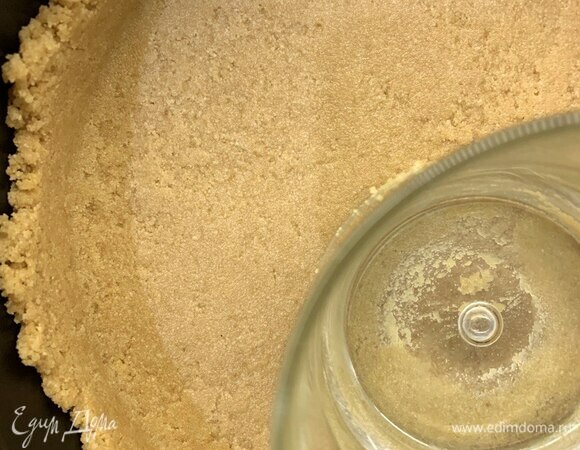 Выложить половину массы в форму, плотно утрамбовать стаканом с плоским дном, затем выложить вторую часть и сделать бортики. Форму с песочной основой поставить в холодильник.