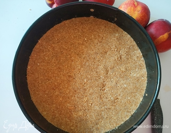 Печенье измельчить до состояния крошки и смешать с растопленным сливочным маслом. Дно разъемной формы диаметром 24 см застелить пергаментной бумагой. Выложить печенье, равномерно распределить и утрамбовать. Убрать в холодильник на 30 минут.