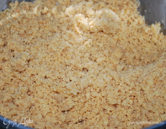 Обжаренную крошку и мелкий миндаль соедините вместе, перемолите с помощью блендера в мелкую крошку, добавьте подтопленное сливочное масло (примерно 30 г). Масла может понадобиться немного, смотрите на состояние крошки, чтобы из нее можно было сделать основу и она не рассыпалась.