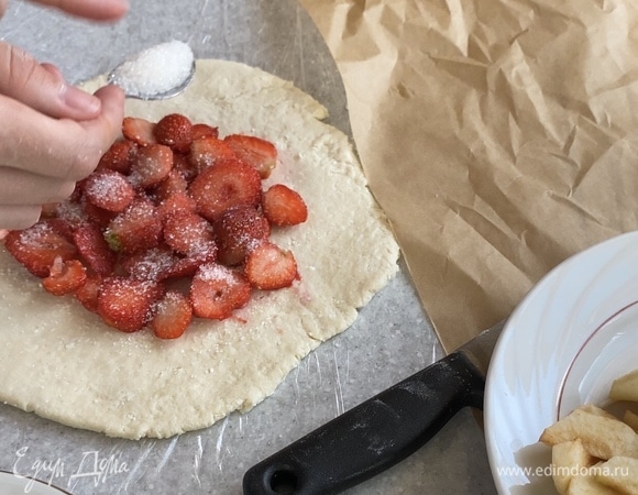 Посередине заготовки выложить ломтики фруктов или ягод, посыпать сахаром и крахмалом.